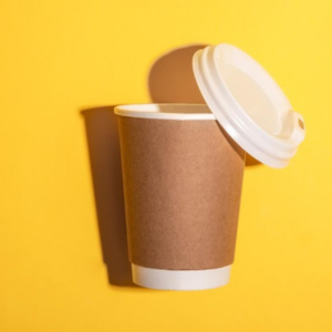 Paper Cup Manufacturer in Delhi Brown single wall paper cup with white lid against a bright yellow background casting a soft shadow.