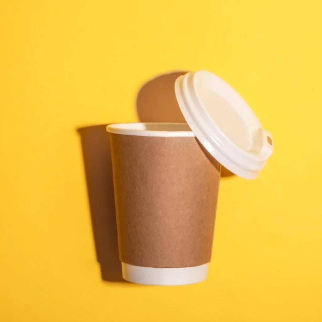 Brown Double wall paper cup with white lid against a bright yellow background casting a soft shadow.