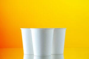 front view paper water cups yellow wall
